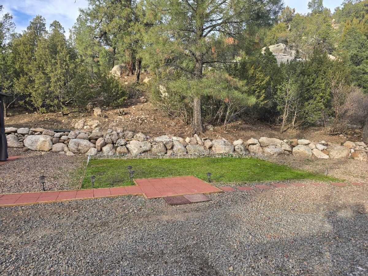 Private grass patch and paver path against the rock wall
